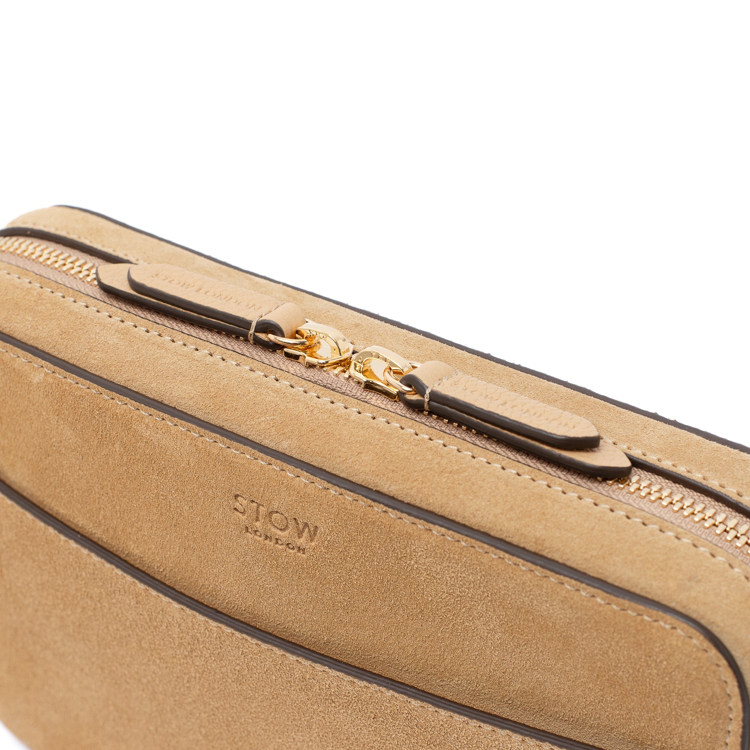 Close up of STOW London's Camera bag in Soft Sand Suede leather featuring gold-coated stainless steel hardware and brand engraved pull tabs on a white background