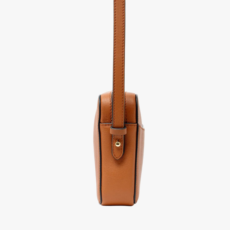 Side view of STOW London's Camera bag in Earth Tan Smooth leather featuring gold-coated stainless steel hardware and detachable crossbody strap on a light grey background