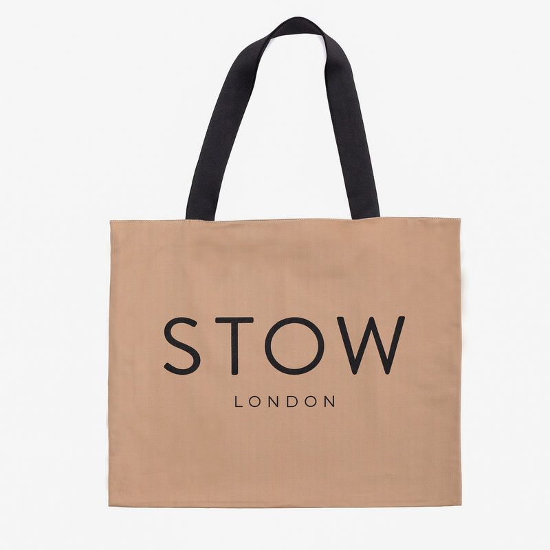 Beige tote bag with black handles and 'STOW LONDON' branding on a white background