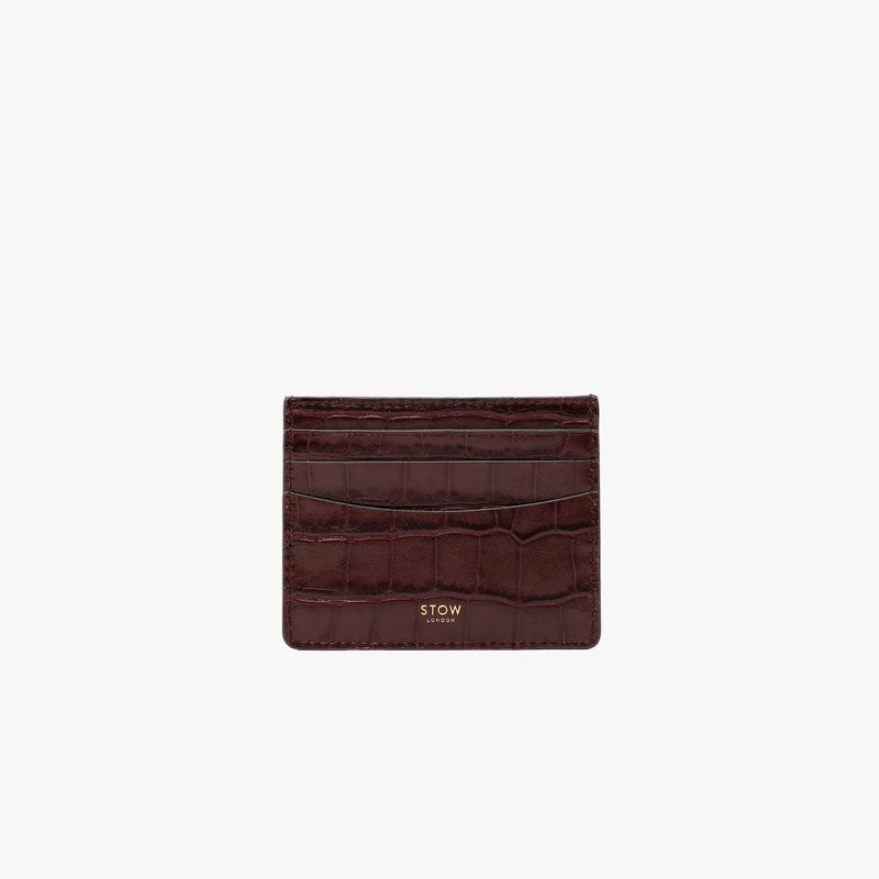 STOW London's Cardholder in Burgundy Embossed Croc leather on a light grey background featuring a fine gold embossed logo on the front bottom. 