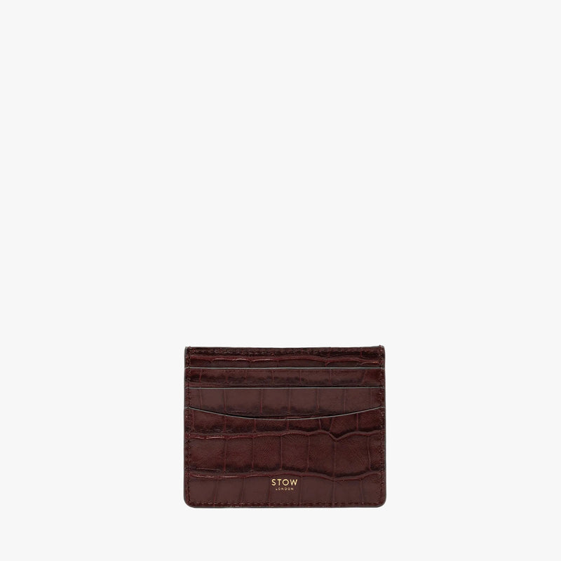 STOW London's Cardholder in Burgundy Embossed Croc leather on a light grey background featuring a fine gold embossed logo on the front bottom. 
