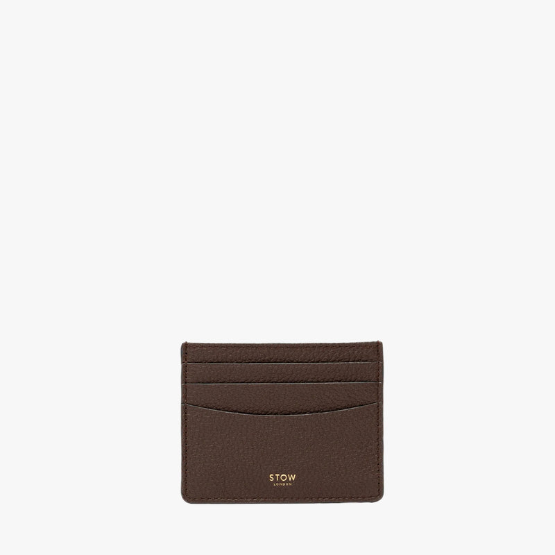 STOW London's Cardholder in Espresso pebbled leather on a light grey background featuring a fine gold embossed logo on the front bottom. 