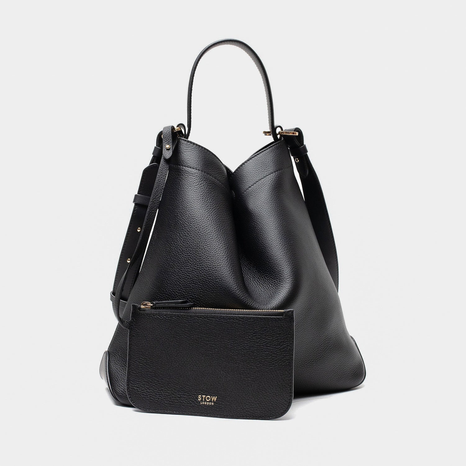 STOW London's Curve bag and matching, detachable interior pouch in Black leather featuring gold-coated stainless steel hardware on a light grey background