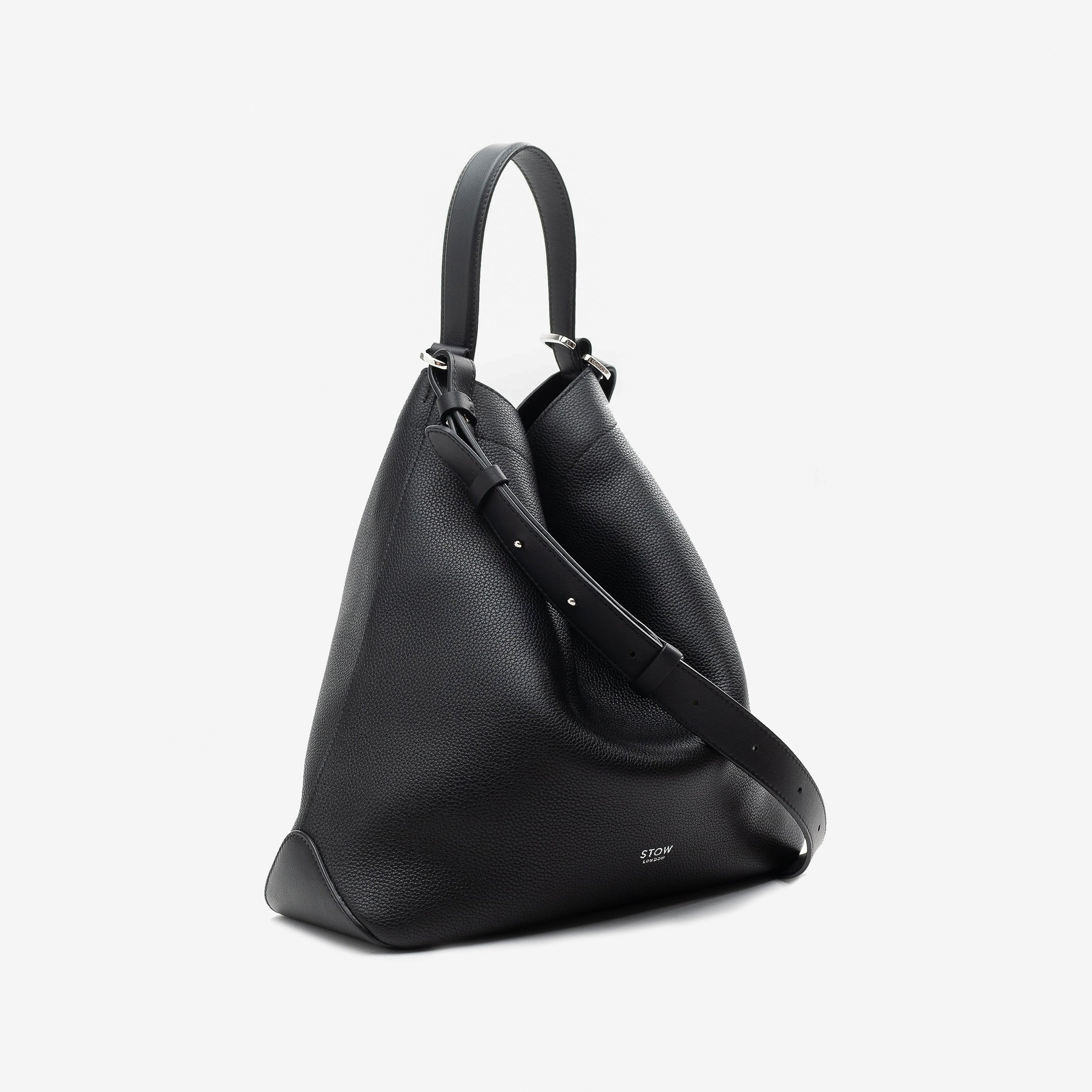 Off-axis view of STOW London's Curve bag in Black pebbled leather featuring silver stainless steel hardware on a light grey background