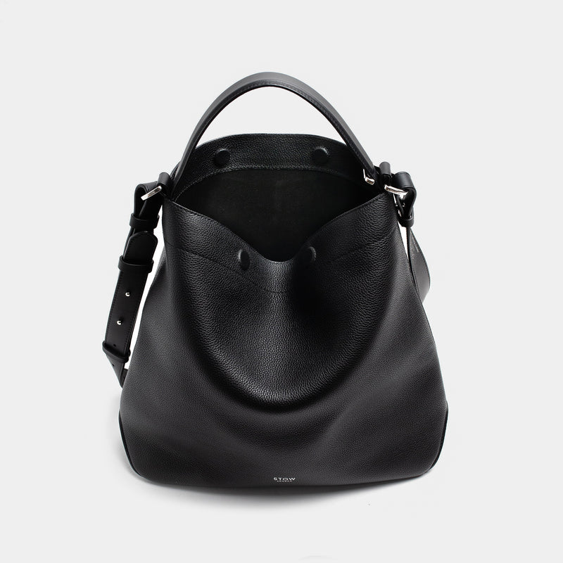 STOW London's Curve bag in Black pebbled leather with magnets open the black suede interior lining featuring silver stainless steel hardware on a light grey background