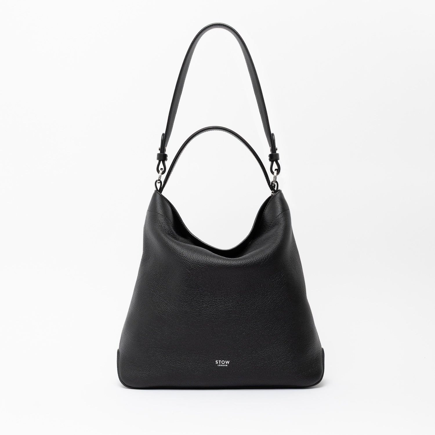 STOW London's Curve in Black leather on a light grey background featuring the detachable shoulder strap and its top handle with silver hardware and details 