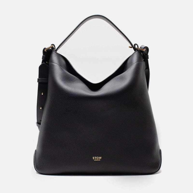 Stow London's Curve bag in Black pebbled leather featuring gold-coated stainless steel hardware on a light grey background