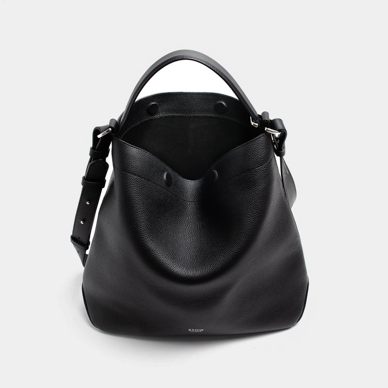Stow London's Curve bag in Black pebbled leather with magnets open showing the black suede interior lining featuring silver stainless steel hardware on a light grey background