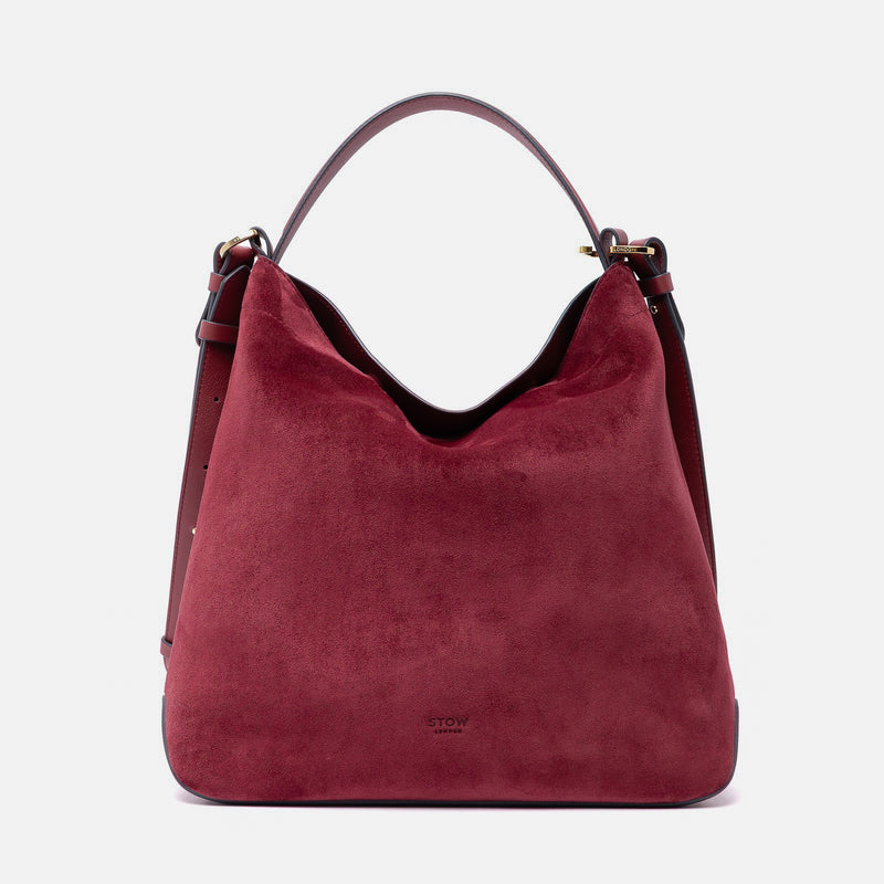 Stow London's Curve bag in Burgundy suede leather featuring gold-coated stainless steel hardware on a light grey background
