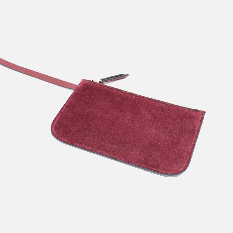 Close up of the detachable interior pouch of Stow London's Curve bag in Burgundy suede leather on a light grey background