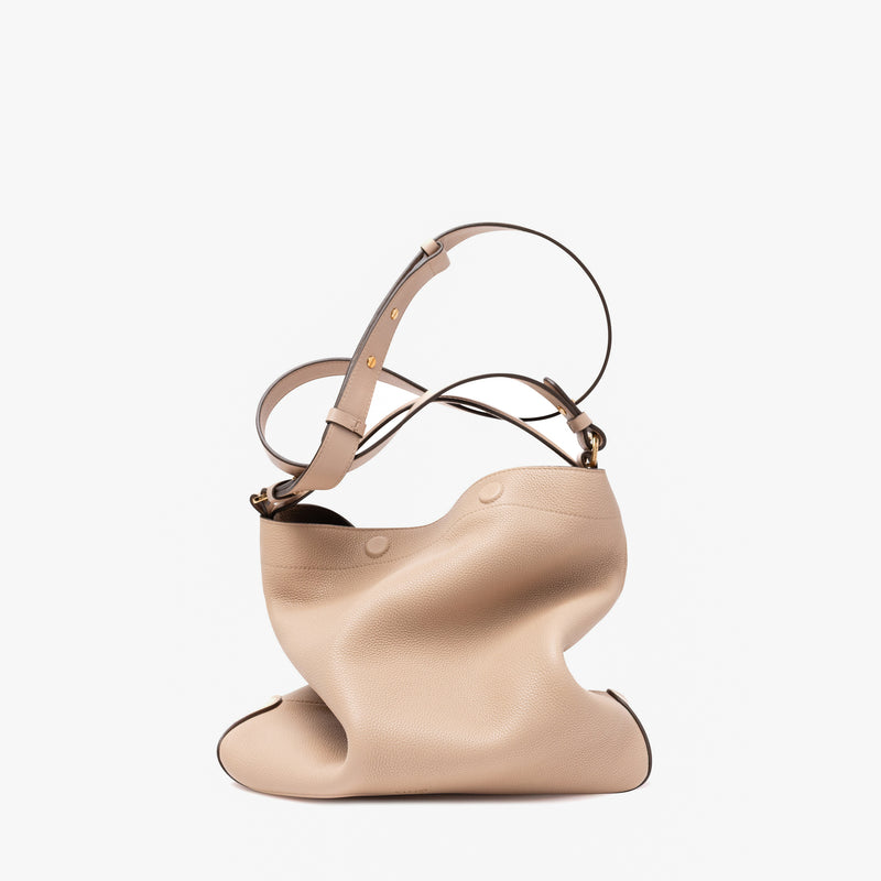 Stow London's Curve bag in Camel pebbled leather featuring gold-coated stainless steel hardware on a light grey background