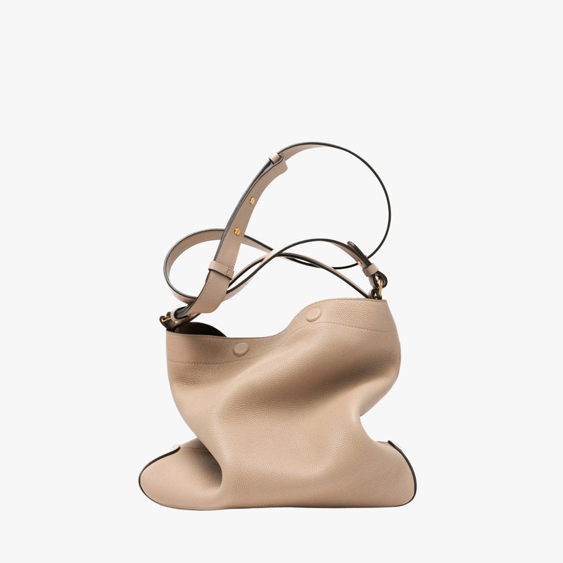 STOW London's Curve bag in Camel pebbled leather featuring its detachable crossbody strap and gold-coated stainless steel hardware on a light grey background
