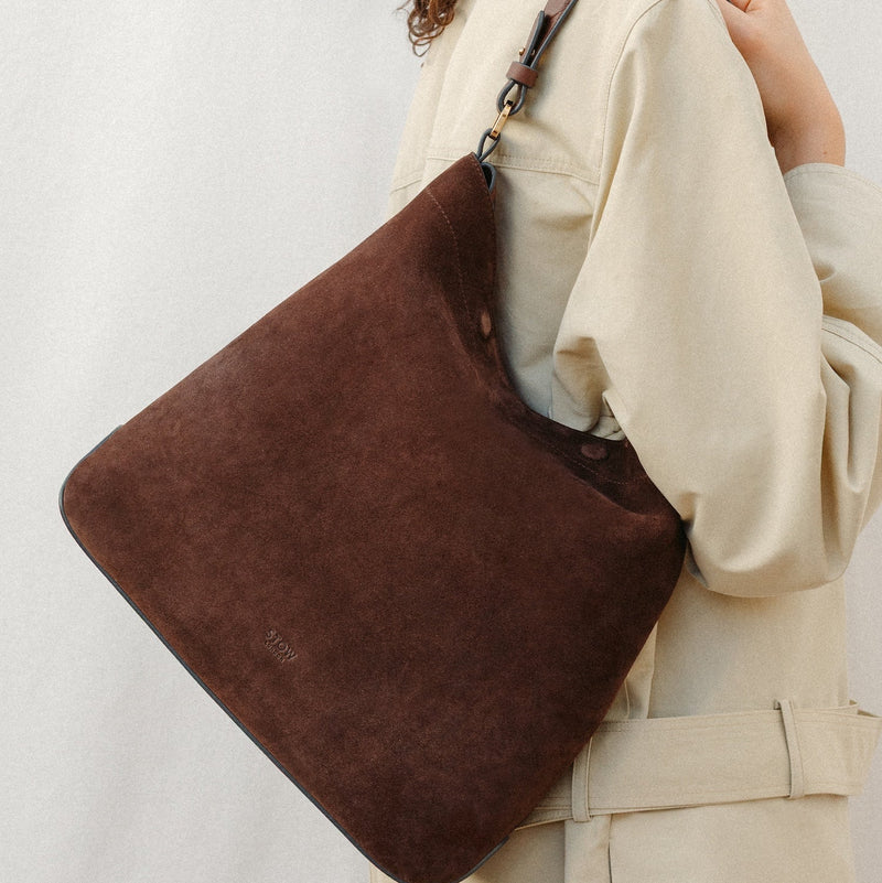 Model wearing STOW London's Curve in Chocolate Suede leather featuring the detachable shoulder strap with gold hardware