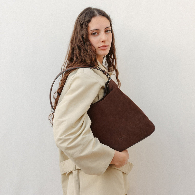 Model wearing STOW London's Curve in Chocolate Suede leather featuring the detachable shoulder strap with gold hardware