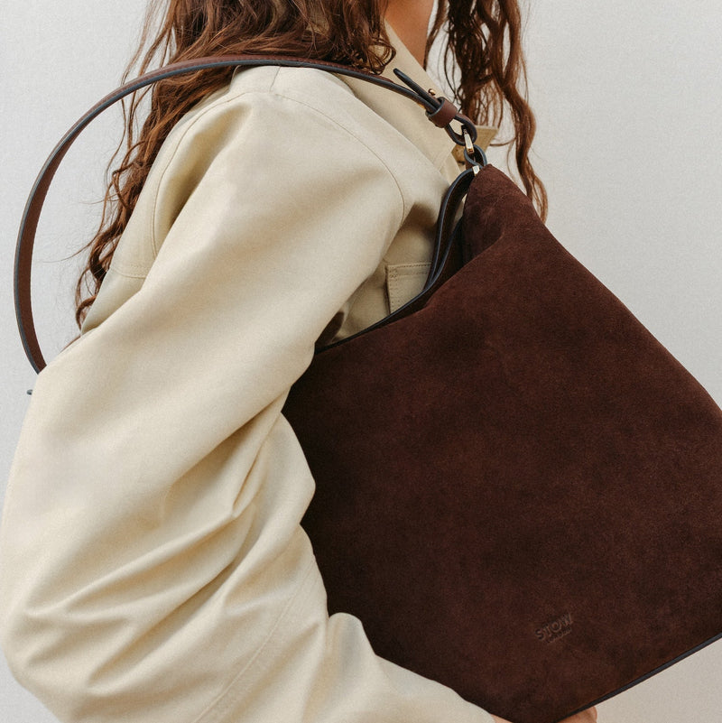 Model wearing STOW London's Curve in Chocolate Suede leather featuring the detachable shoulder strap with gold hardware