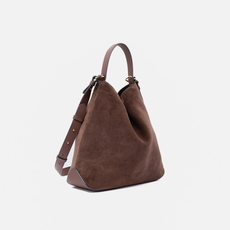 Off-axis shot of Stow London's Curve bag in Chocolate suede leather in a triangular shape featuring gold-coated stainless steel hardware on a light grey background