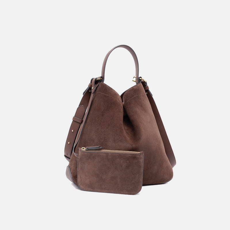 Stow London's Curve bag and matching, detachable pouch in Chocolate suede leather featuring gold-coated stainless steel hardware on a light grey background