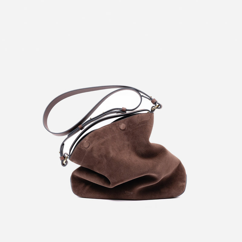Stow London's Curve bag and detachable crossbody strap in Chocolate suede leather featuring gold-coated stainless steel hardware on a light grey background