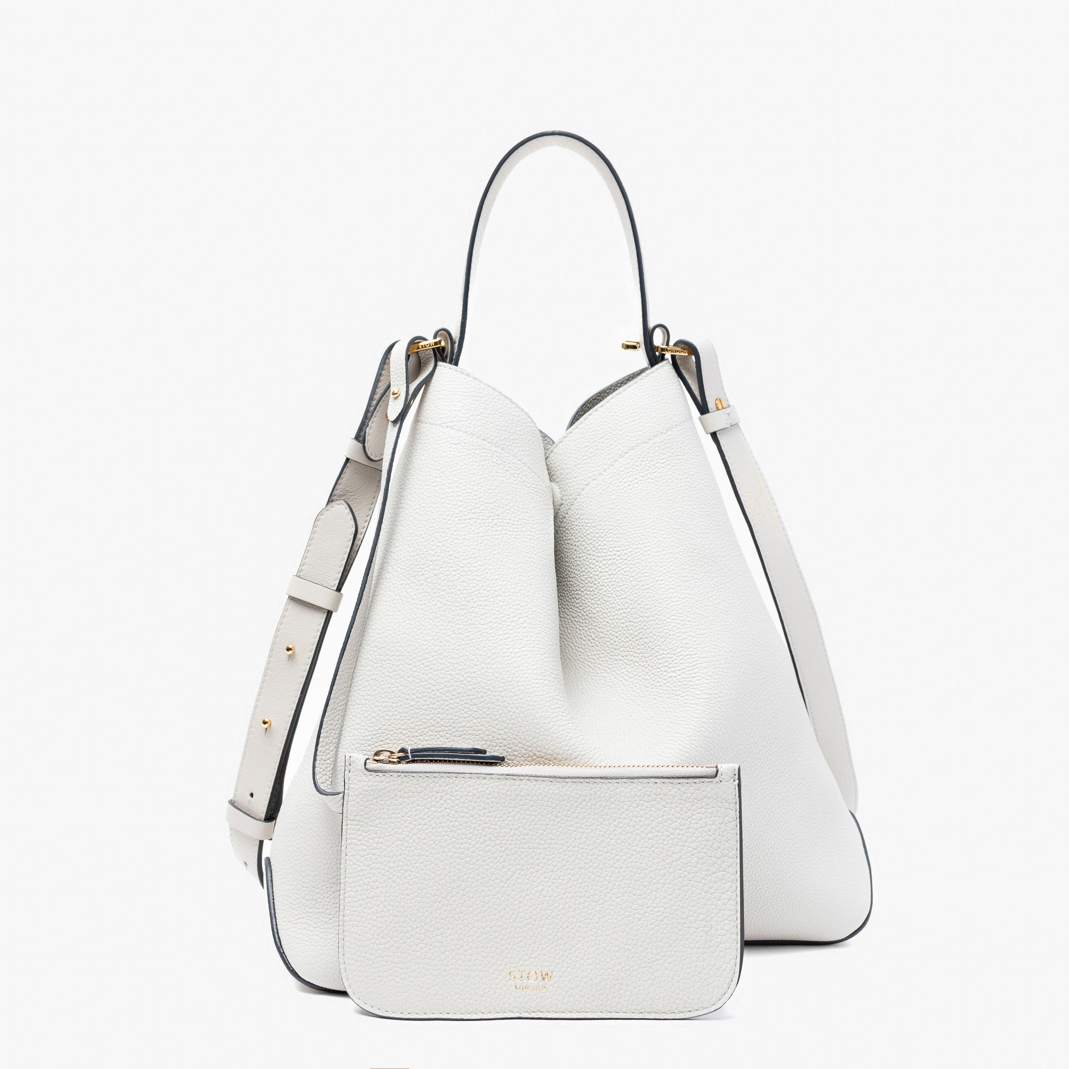 Stow London's Curve bag in Cloud Grey pebbled leather featuring the matching, detachable interior pouch and gold-coated stainless steel hardware on a light grey background