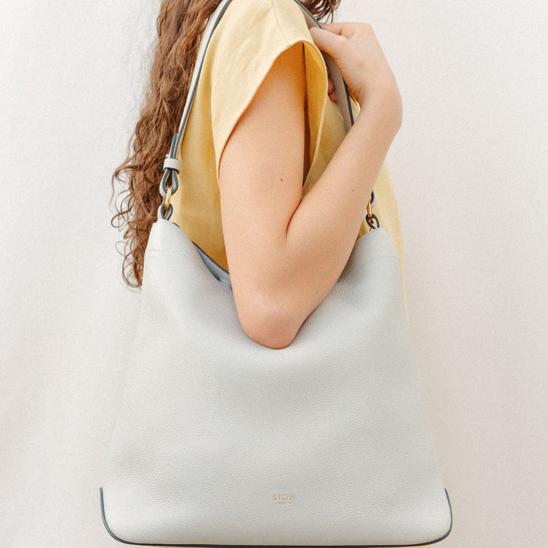 Model wearing STOW London's Curve in Mocha leather featuring the detachable shoulder strap with gold hardware and details 