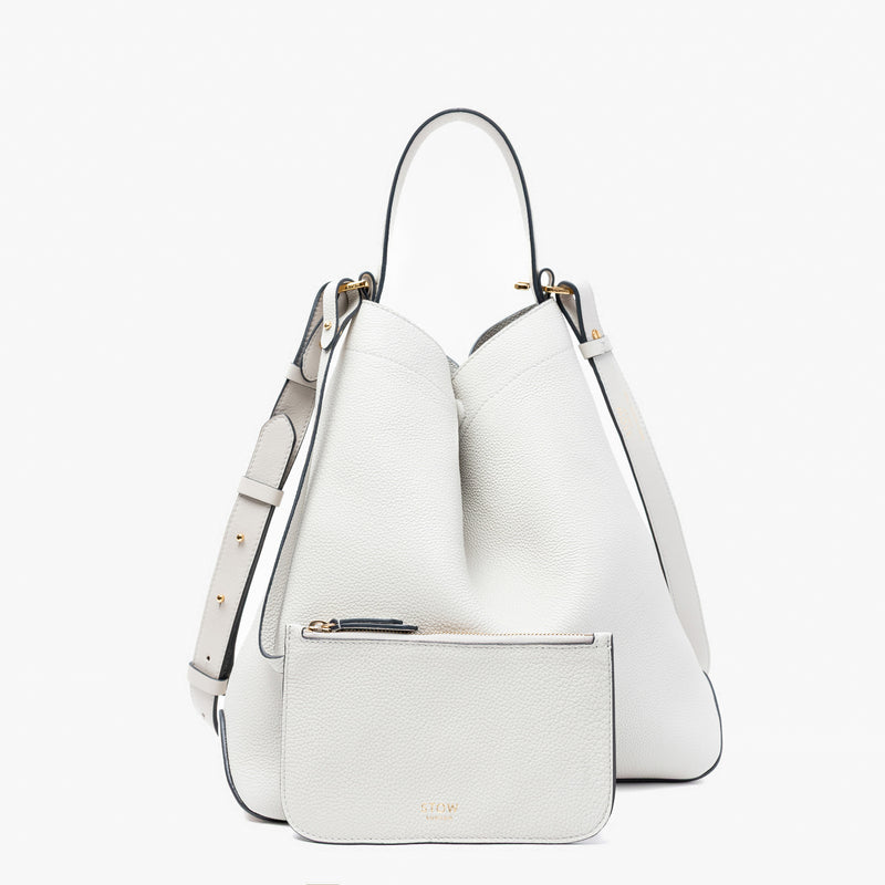 Stow London's Curve bag in Cloud Grey pebbled leather and detachable interior pouch featuring gold-coated stainless steel hardware on a light grey background