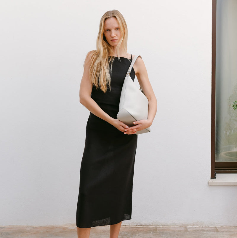 Model wearing STOW London's Curve in Cloud Grey leather featuring the detachable shoulder strap with gold hardware and details 