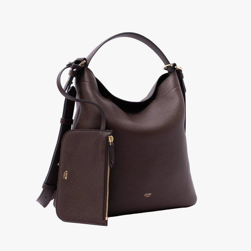 STOW London's Curve Bag in Espresso pebbled leather featuring the detachable, matching interior pouch and gold-coated stainless steel hardware on a light grey background