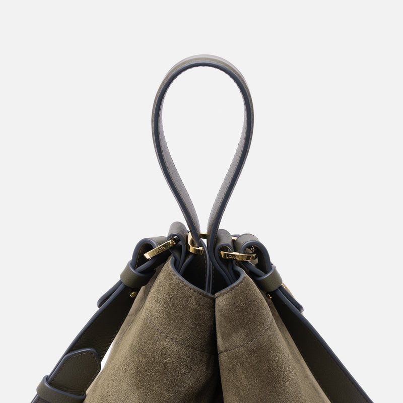 Close-up of handle of Stow London's Curve bag in Dark Green suede leather featuring gold-coated stainless steel hardware and clip on a light grey background