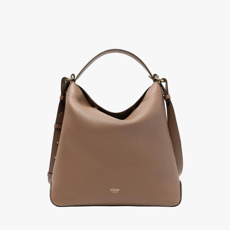 STOW London's Curve bag in Mocha pebbled leather featuring gold-coated stainless steel hardware on a light grey background