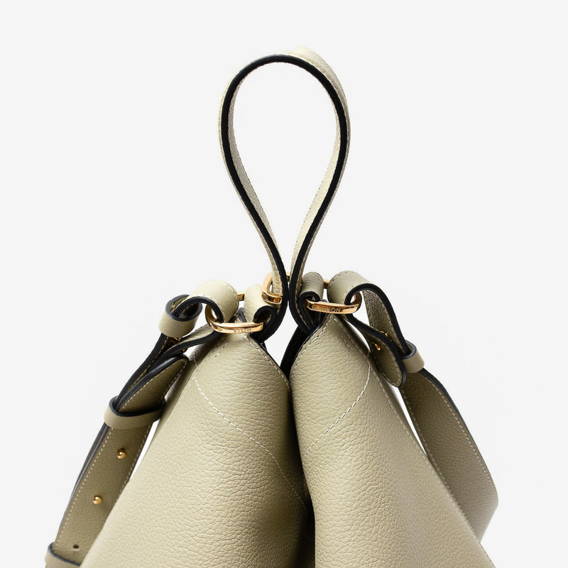 Close-up of strap of Stow London's Curve bag in Pale Green pebbled leather featuring gold-coated stainless steel hardware and clip and detachable strap on a light grey background