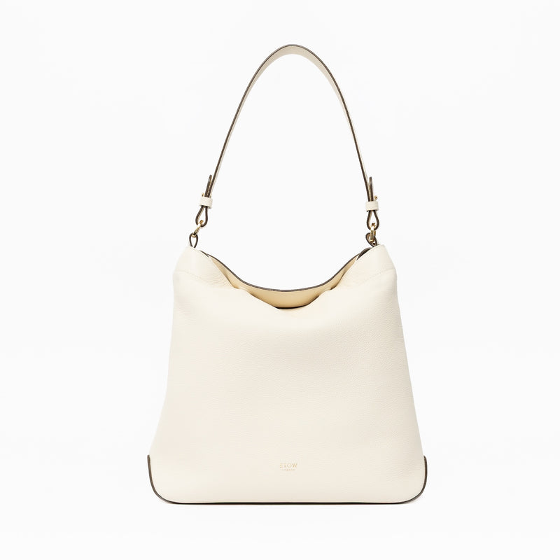STOW London's Curve in Spring Moon leather on a light grey background featuring the detachable shoulder strap with gold hardware and details 