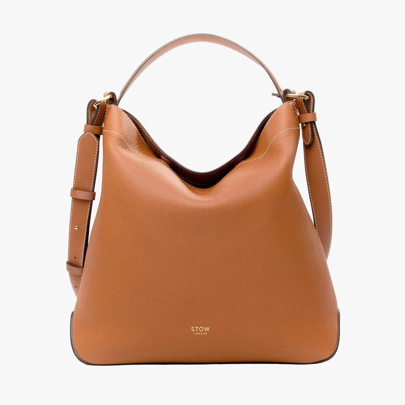 STOW London's Curve in Earth tan pebbled leather and detachable crossbody strap on a light grey background 