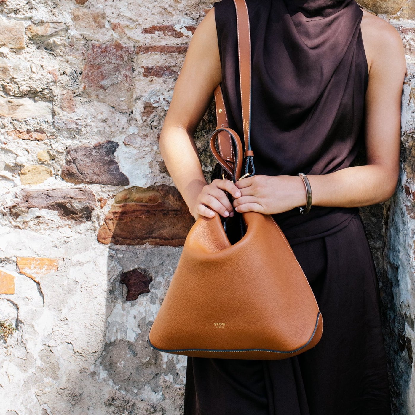 STOW London Curve Bag in Earth Tan leather held by model in Tangiers photo shoot.