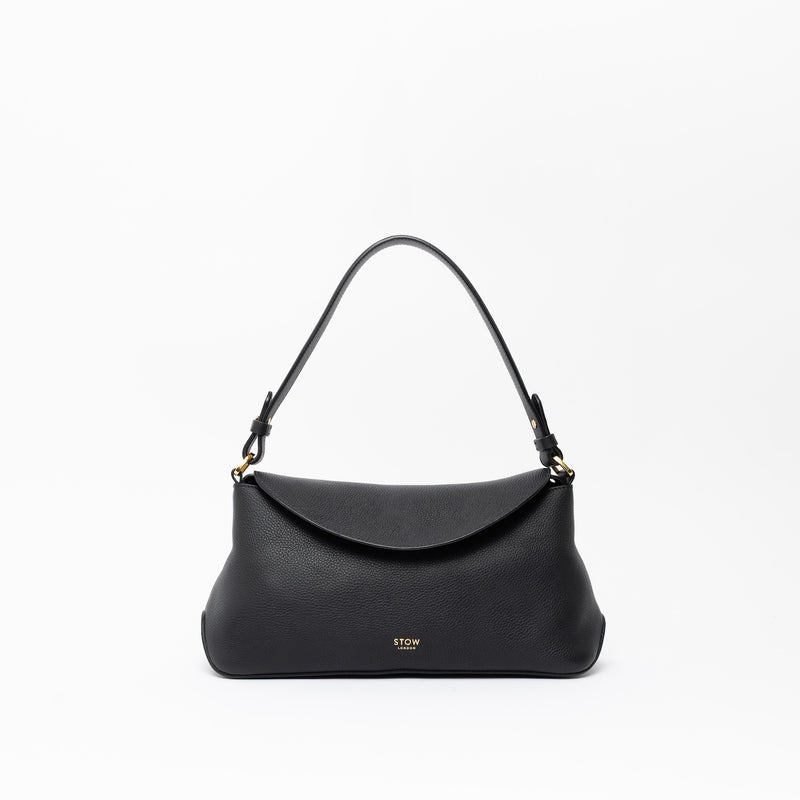 STOW London's East West in Black leather on a light grey background featuring the detachable shoulder strap with gold hardware and details 