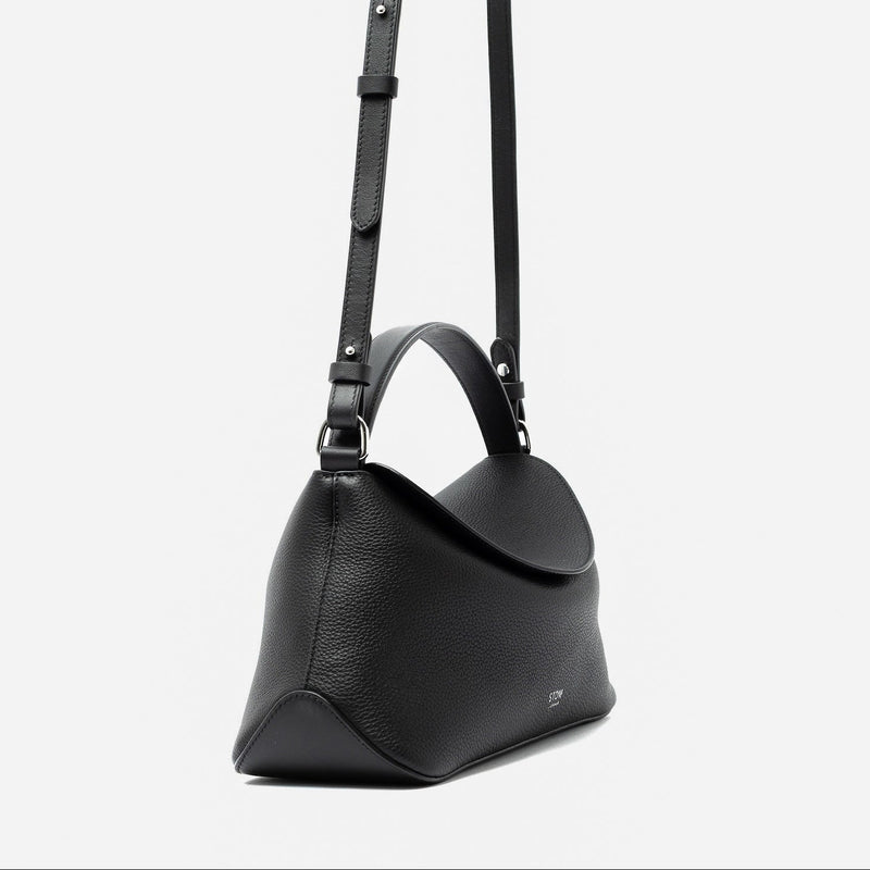 Side view of STOW London's East West and detachable crossbody strap in Black pebbled leather featuring silver stainless steel hardware on a light grey background