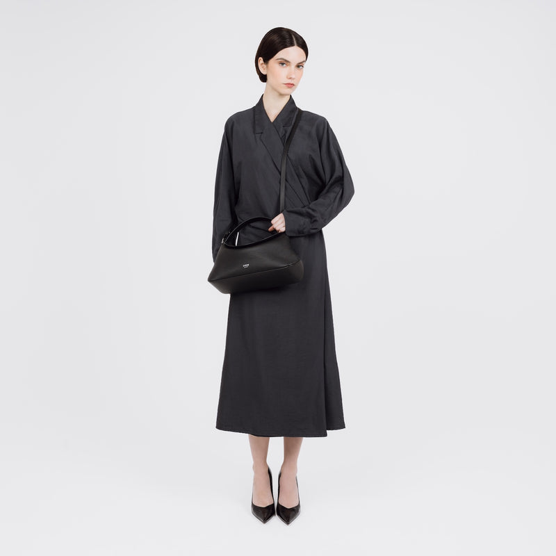 Model wearing STOW London's East West bag in Black pebbled and smooth leather crossbody featuring silver stainless steel hardware on a white background