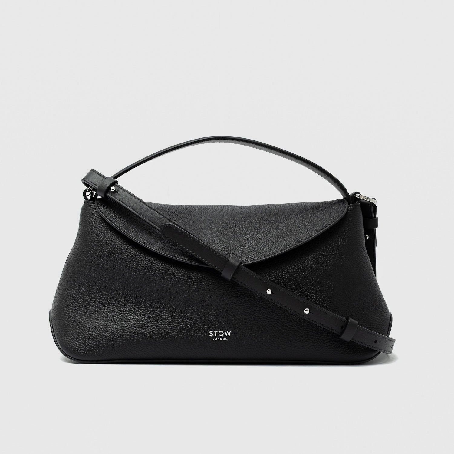 STOW London's East West in Black pebbled leather and detachable crossbody strap featuring silver stainless steel hardware on a light grey background