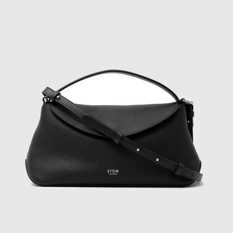 STOW London's East West in Black pebbled leather and detachable crossbody strap featuring silver stainless steel hardware on a light grey background