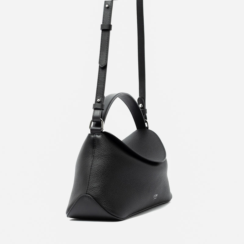 Side view of STOW London's East West and detachable crossbody strap in Black pebbled leather featuring silver stainless steel hardware on a light grey background