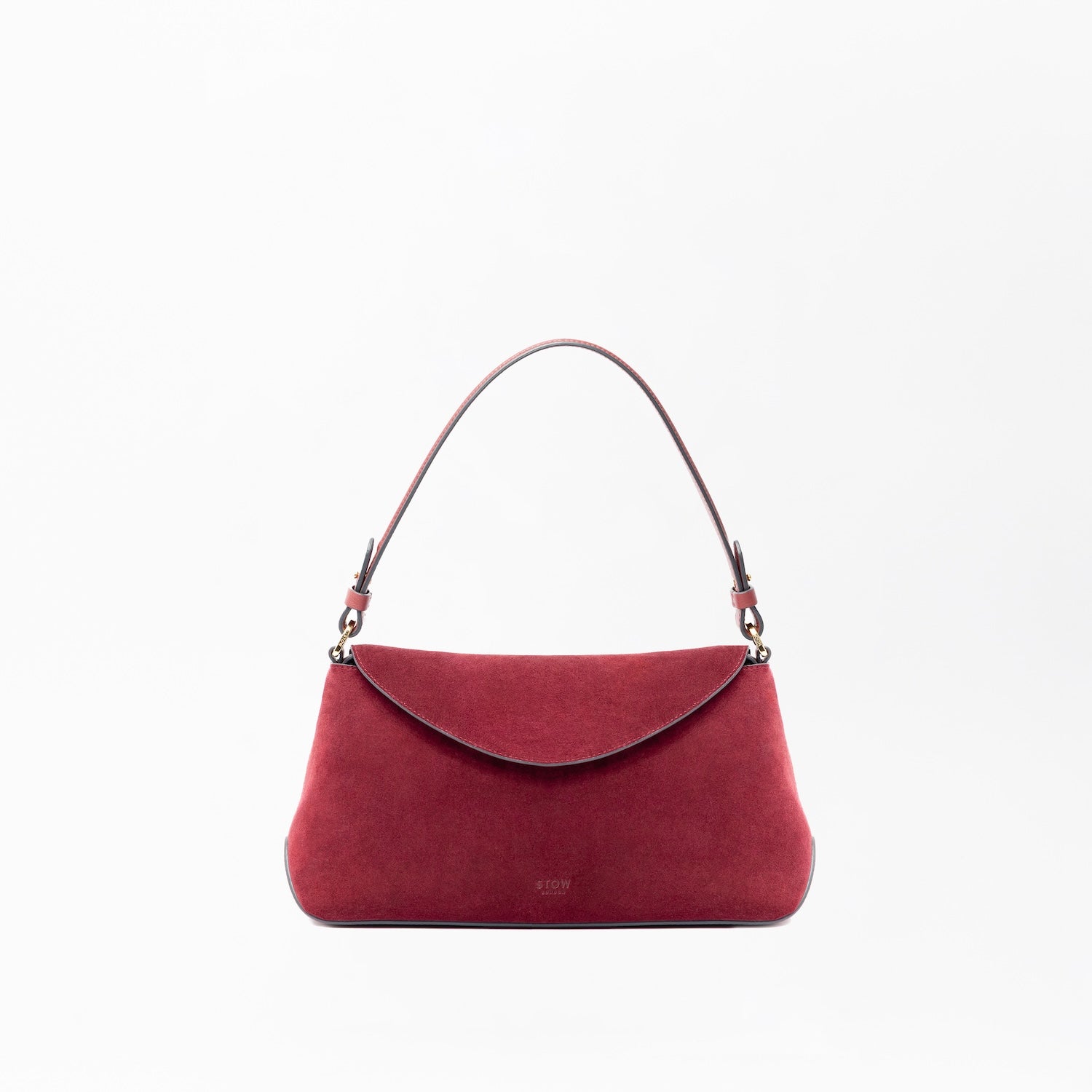 STOW London's East West in Burgundy suede leather on a light grey background featuring the detachable shoulder strap with gold hardware and details 