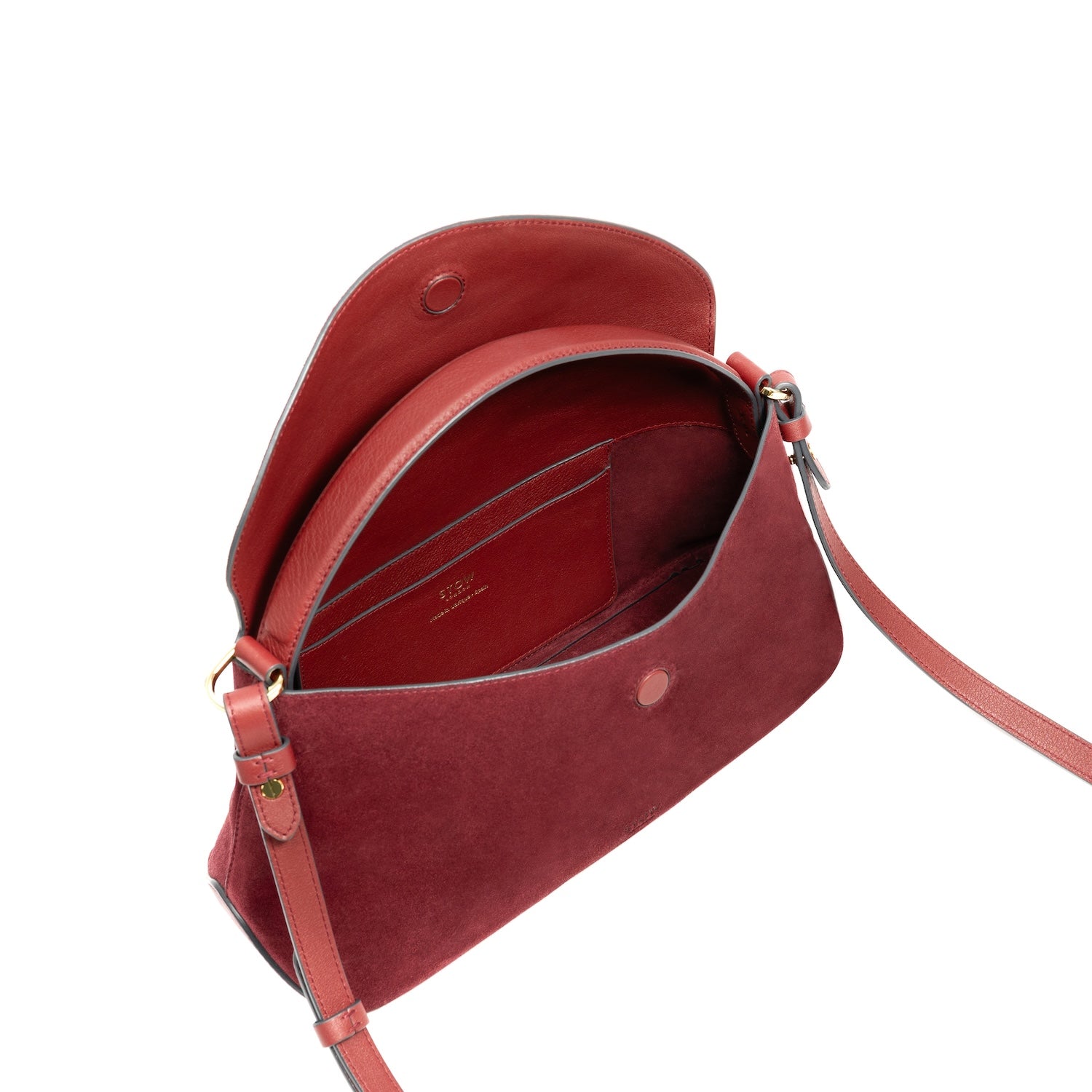 Top angled view of STOW London's East West bag in Burgundy Suede leather with flap open showing interior cad holder pocket featuring gold-coated stainless steel hardware on a white background