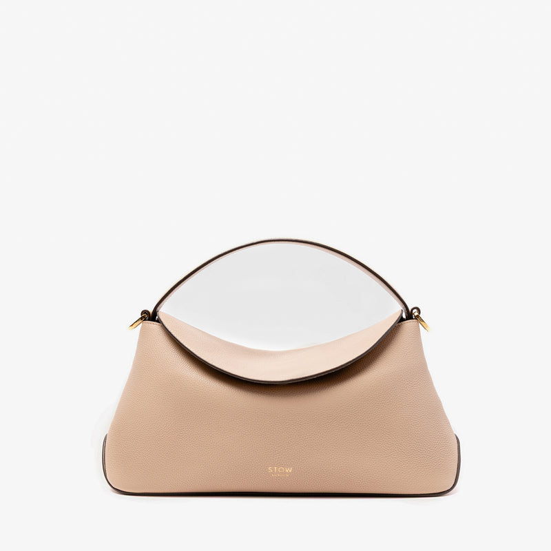 STOW London's East West in Camel pebbled leather featuring gold-coated stainless steel hardware on a light grey background