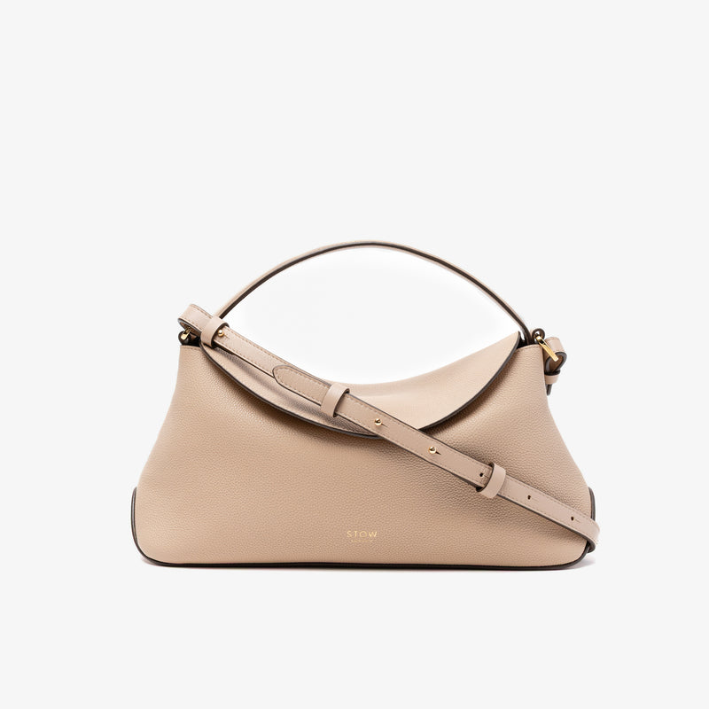 STOW London's East West in Camel pebbled leather and detachable crossbody strap featuring gold-coated stainless steel hardware on a light grey background