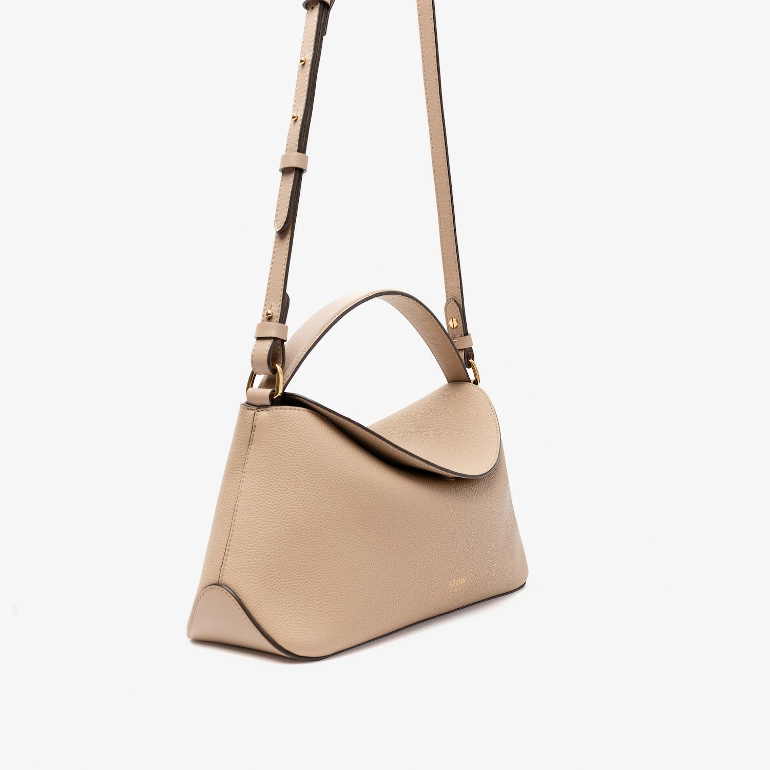 Off-axis view of STOW London's East West in Camel pebbled leather and detachable crossbody strap featuring gold-coated stainless steel hardware on a light grey background