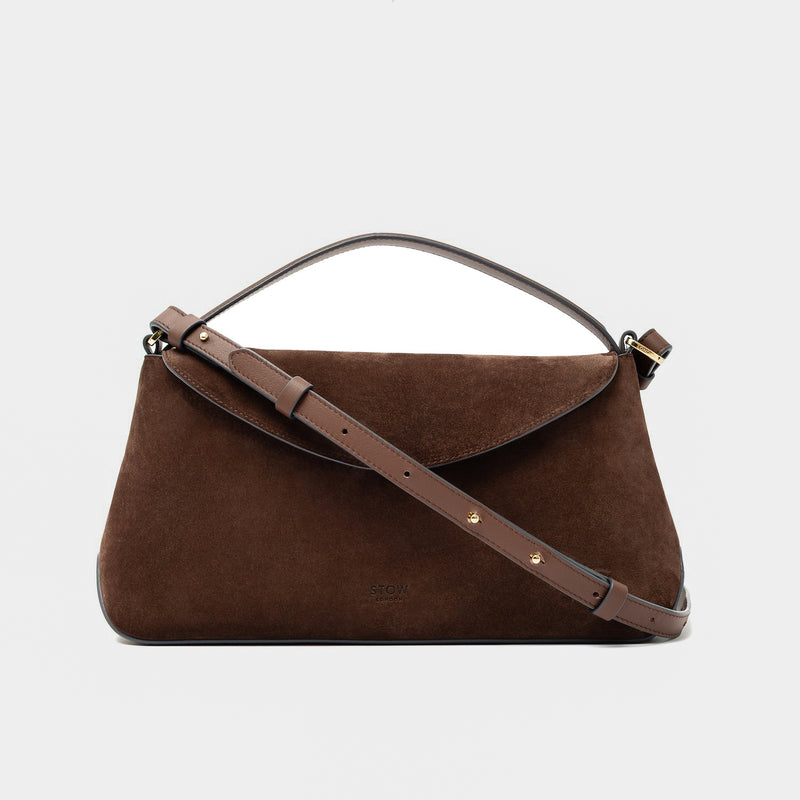 STOW London's East West in Chocolate suede leather and detachable crossbody strap featuring gold-coated stainless steel hardware on a light grey background