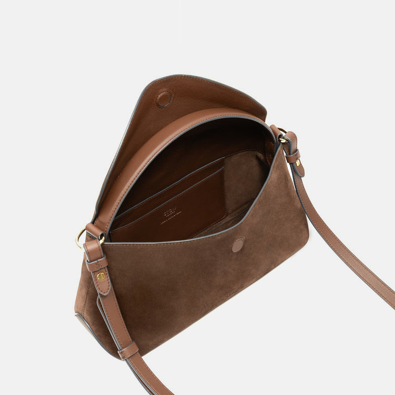 STOW London's East West in Chocolate suede leather with flap open showing suede interior and slip pocket featuring gold-coated stainless steel hardware on a light grey background