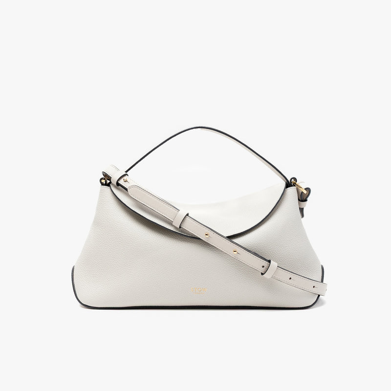 STOW London's East West in Cloud Grey pebbled leather and detachable crossbody strap featuring gold-coated stainless steel hardware on a light grey background