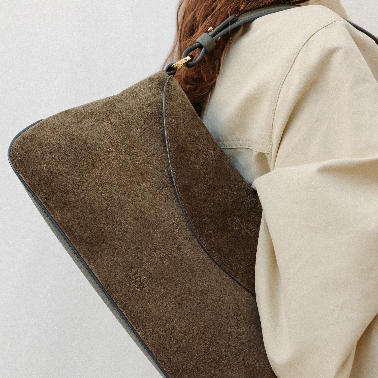 Model wearing STOW London's East West in Dark Green suede leather featuring the detachable shoulder strap with gold hardware