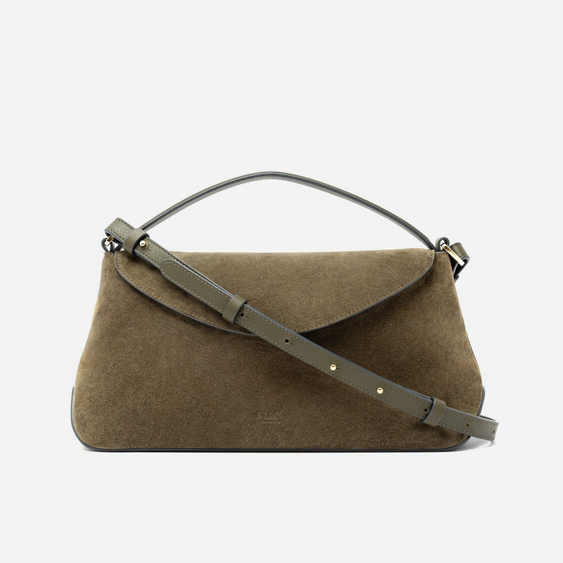 STOW London's East West in Dark Green suede leather and detachable crossbody strap featuring gold-coated stainless steel hardware on a light grey background