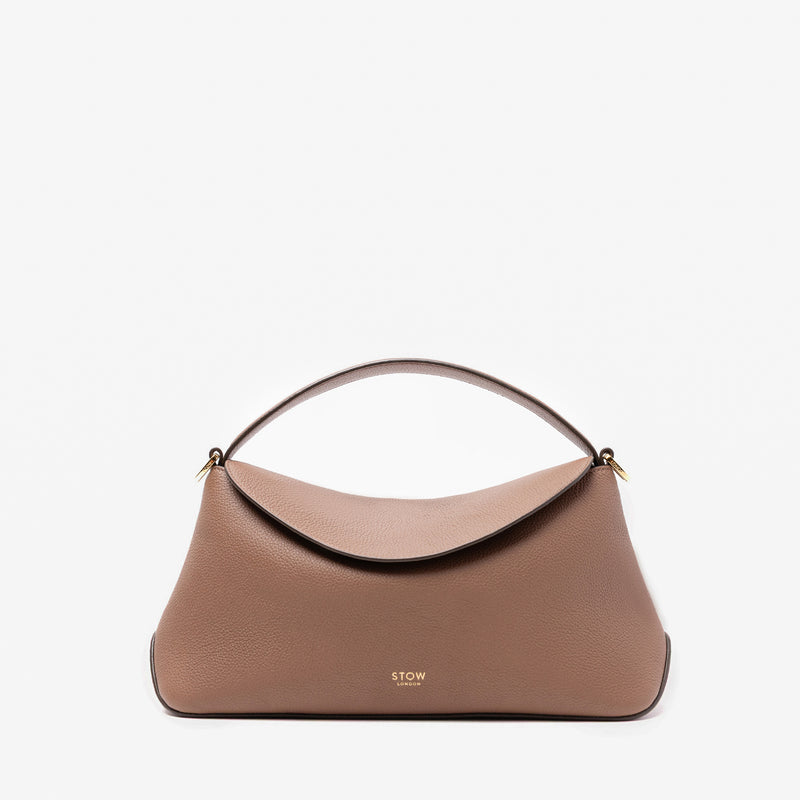 STOW London's East West in Mocha pebbled leather featuring gold-coated stainless steel hardware on a light grey background